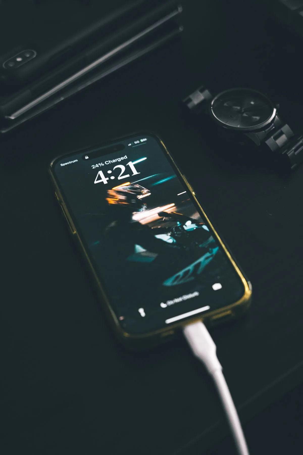 A smartphone connected to a charging cable on a wooden table
