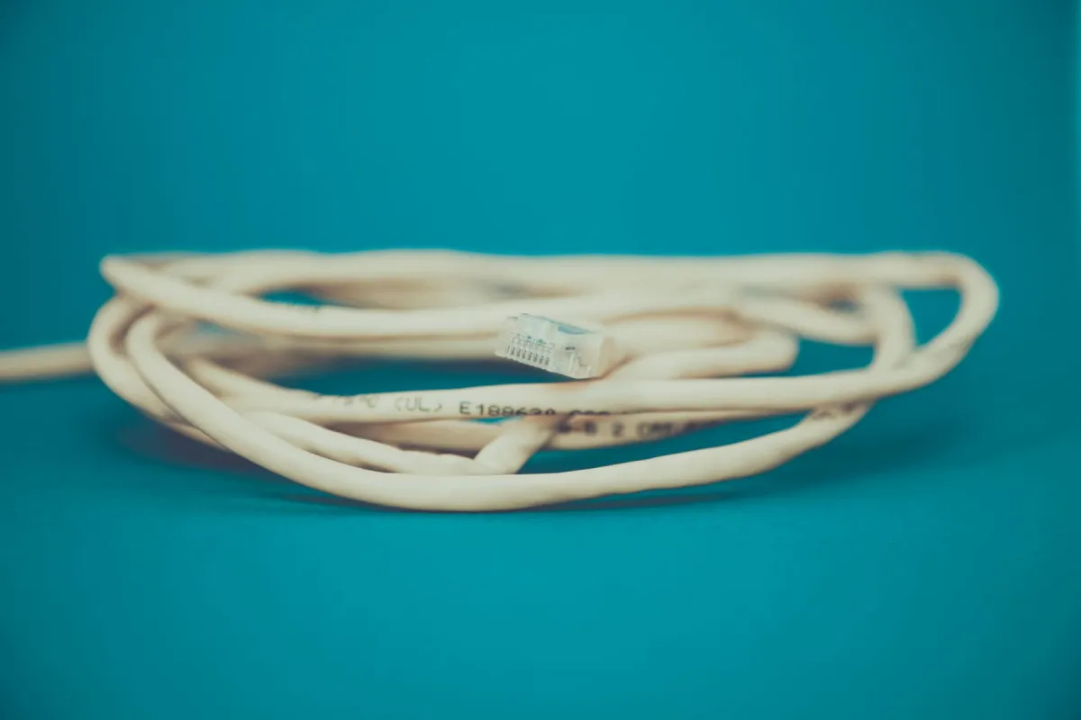 Coiled Ethernet cable with a clear connector on a teal surface