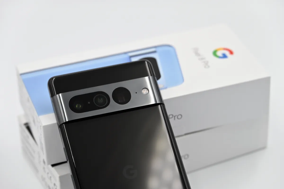 Back of a dark Google Pixel phone resting diagonally against a white Pixel product box.