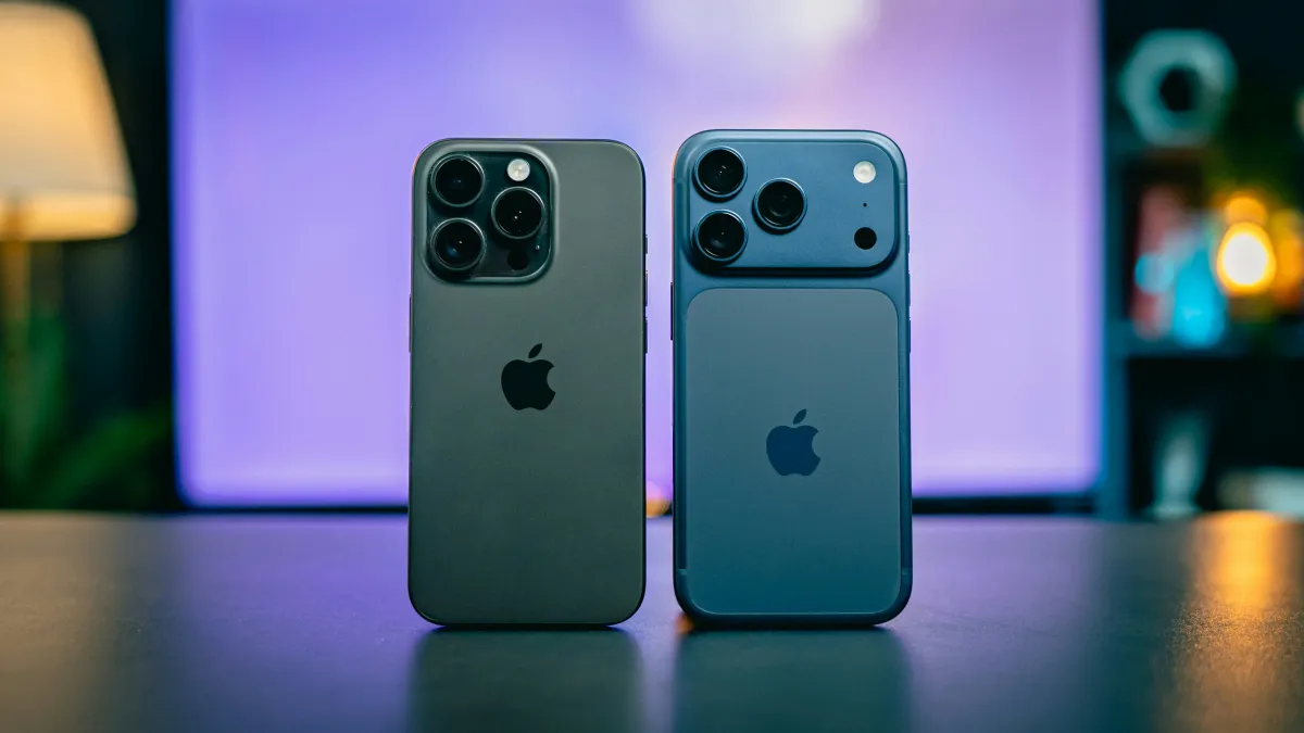 Two iPhones standing side by side with their backs toward the camera against a purple-lit background.