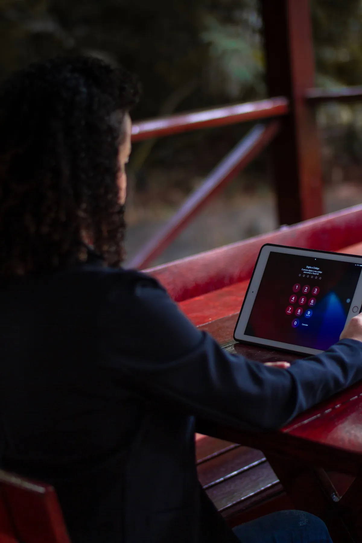 A person using a tablet with a passcode screen at an outdoor table.