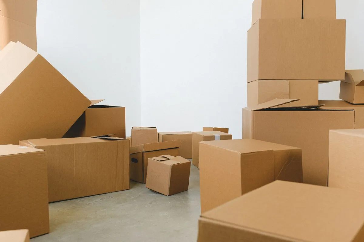 Cardboard moving boxes of different sizes stacked in a bright room.