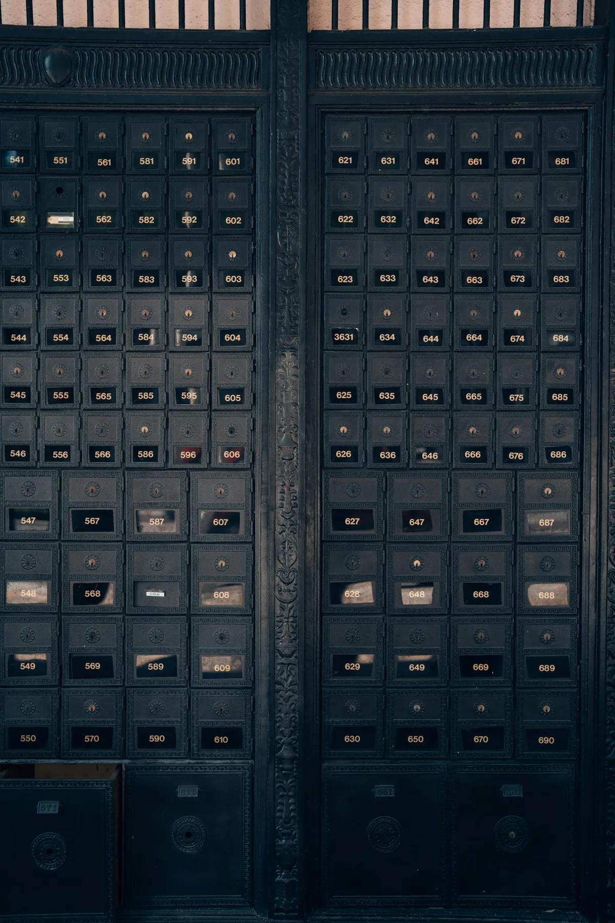 Rows of dark metal post-office mailboxes with individual numbered doors.